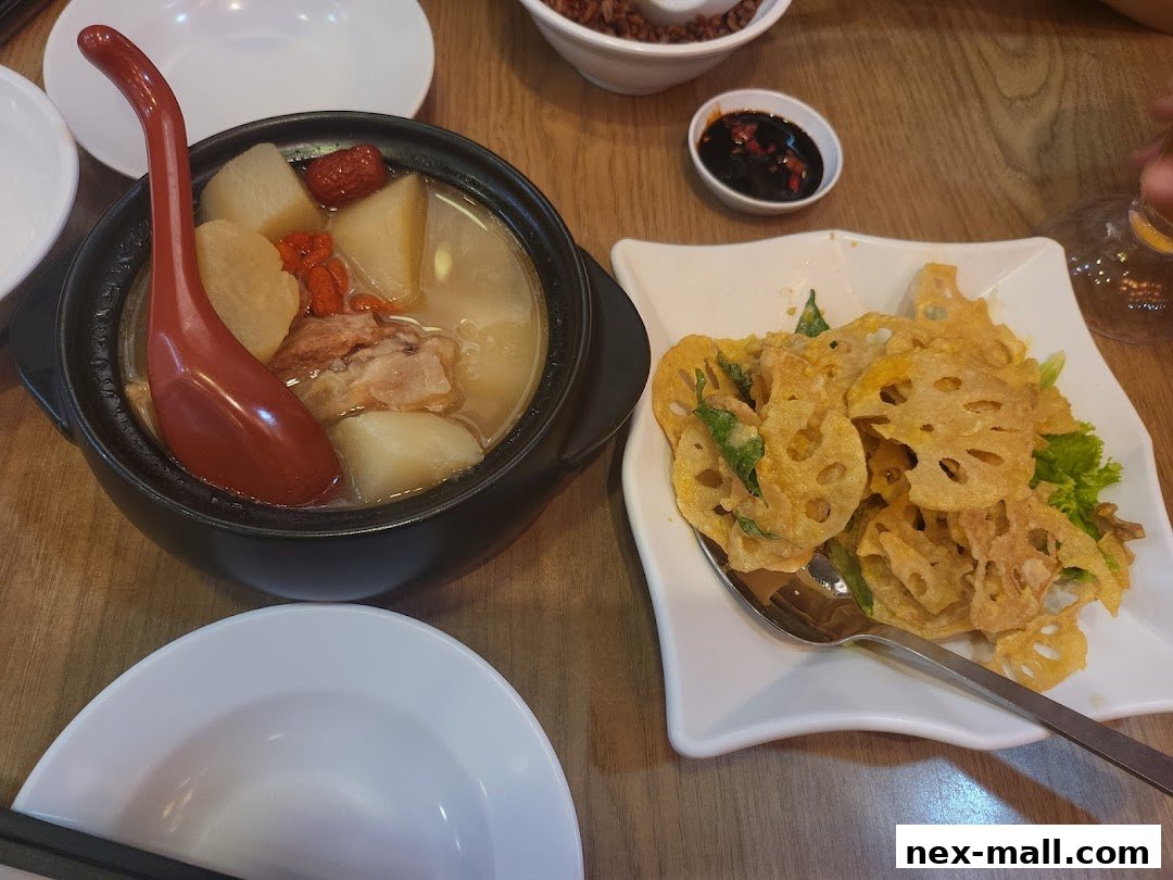 A steaming pot of herbal soup with radish and goji berries next to crispy fried lotus root.