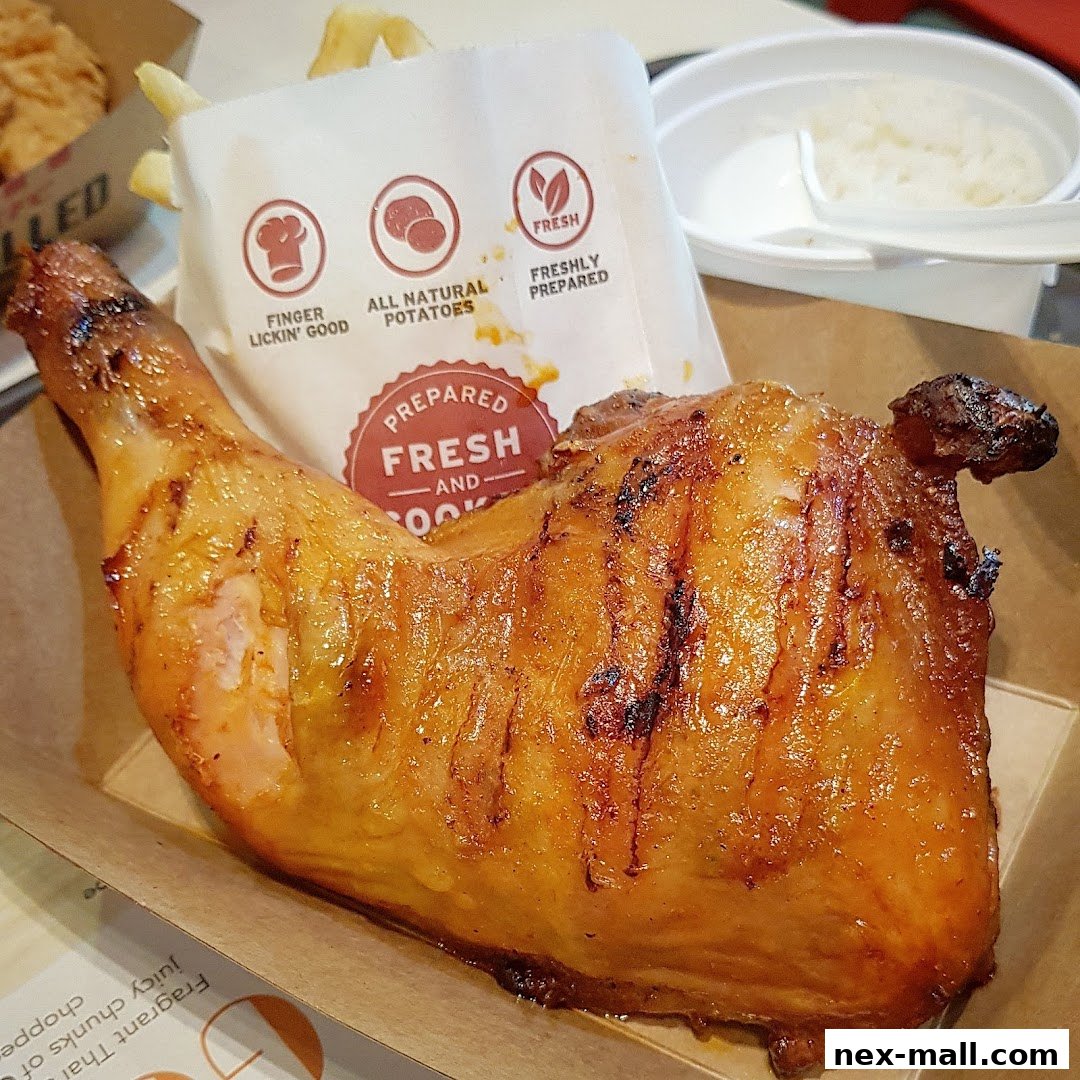 A close-up of a juicy, grilled chicken leg quarter with fries and rice.