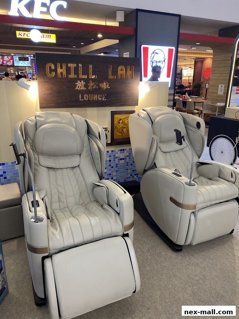 Two luxurious white massage chairs are displayed in front of a 'Chill Lah Lounge' sign.