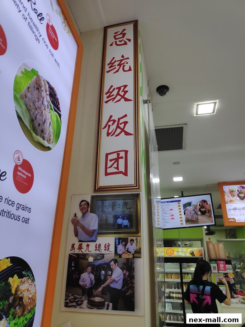 A shop interior with a menu board, photos of a politician, and a display of food items.