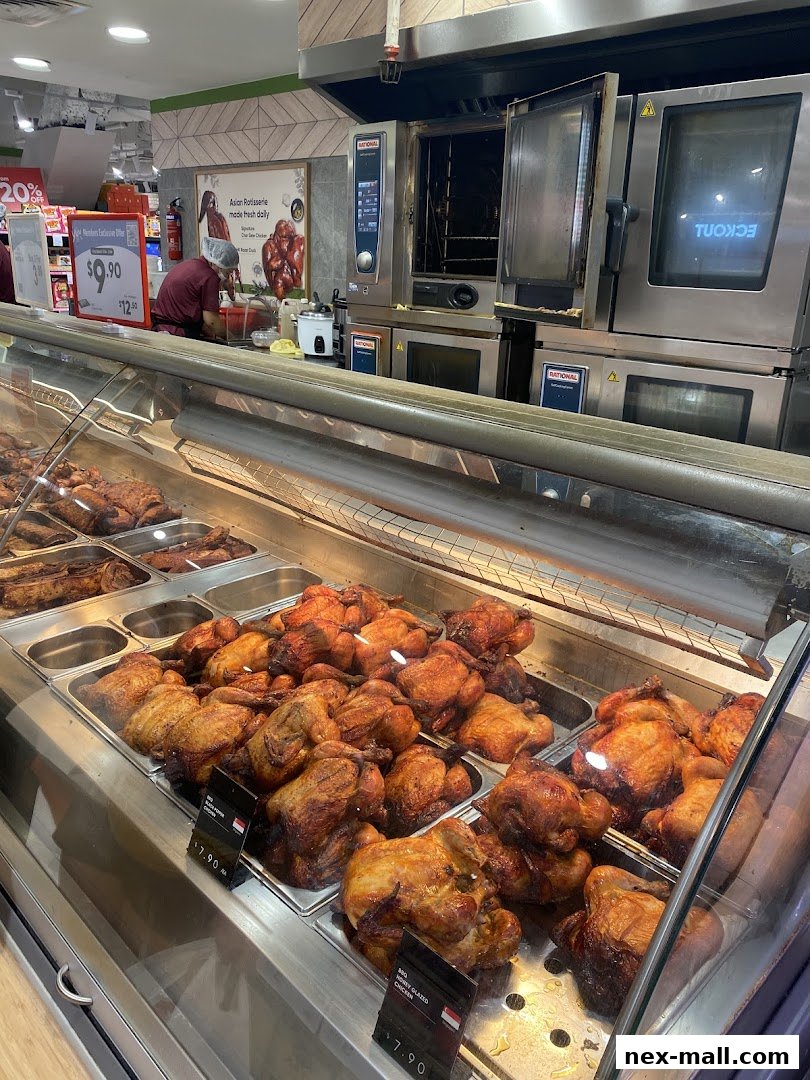 A display of freshly roasted chickens and other meats in a refrigerated case at a grocery store.