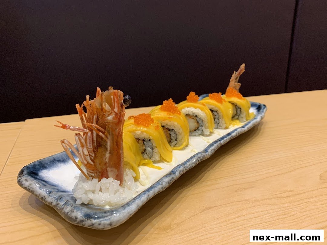 A plate of sushi rolls topped with mango and roe, garnished with a fried shrimp.