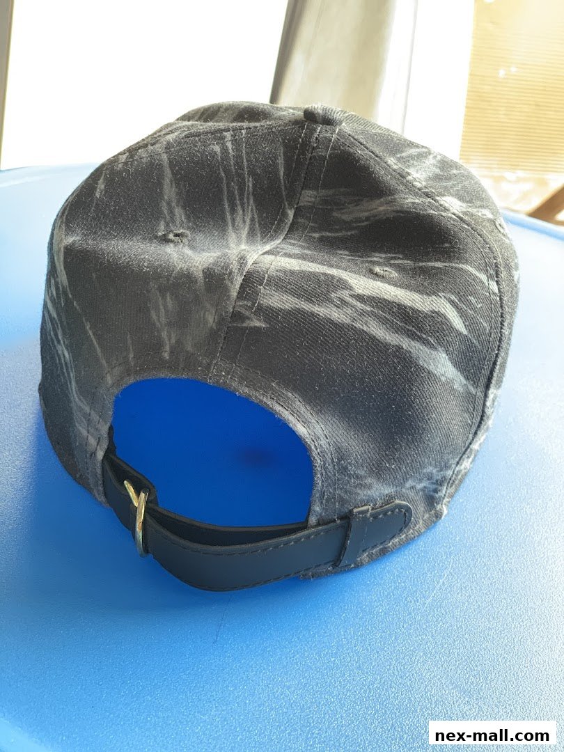 A close-up view of the back of a black baseball cap with a marble-like pattern.