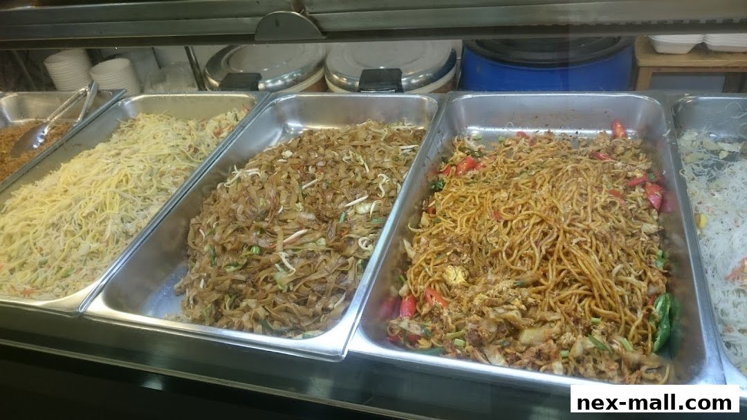 A display of various noodle dishes and fried rice in metal trays.