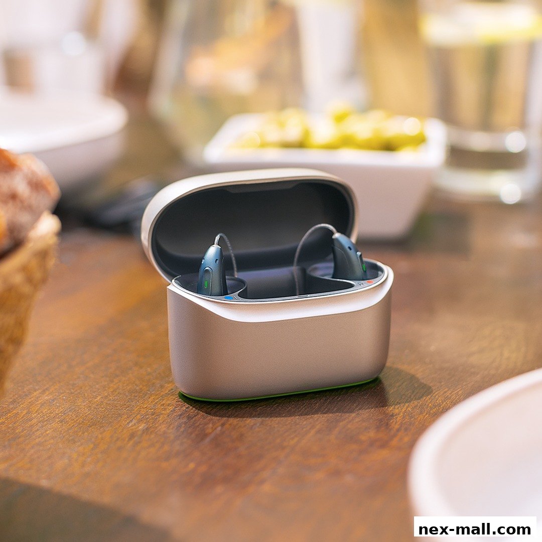A pair of modern hearing aids in a charging case on a wooden table.