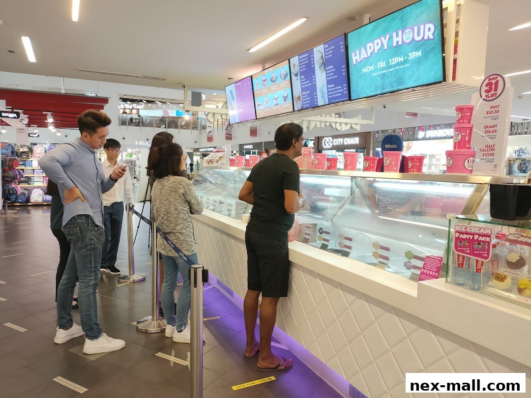 Customers queue at a Baskin-Robbins ice cream shop with a happy hour promotion displayed.