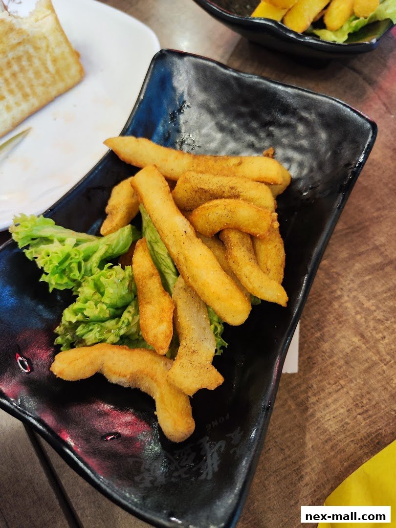 A black plate filled with crispy french fries and a side of lettuce.