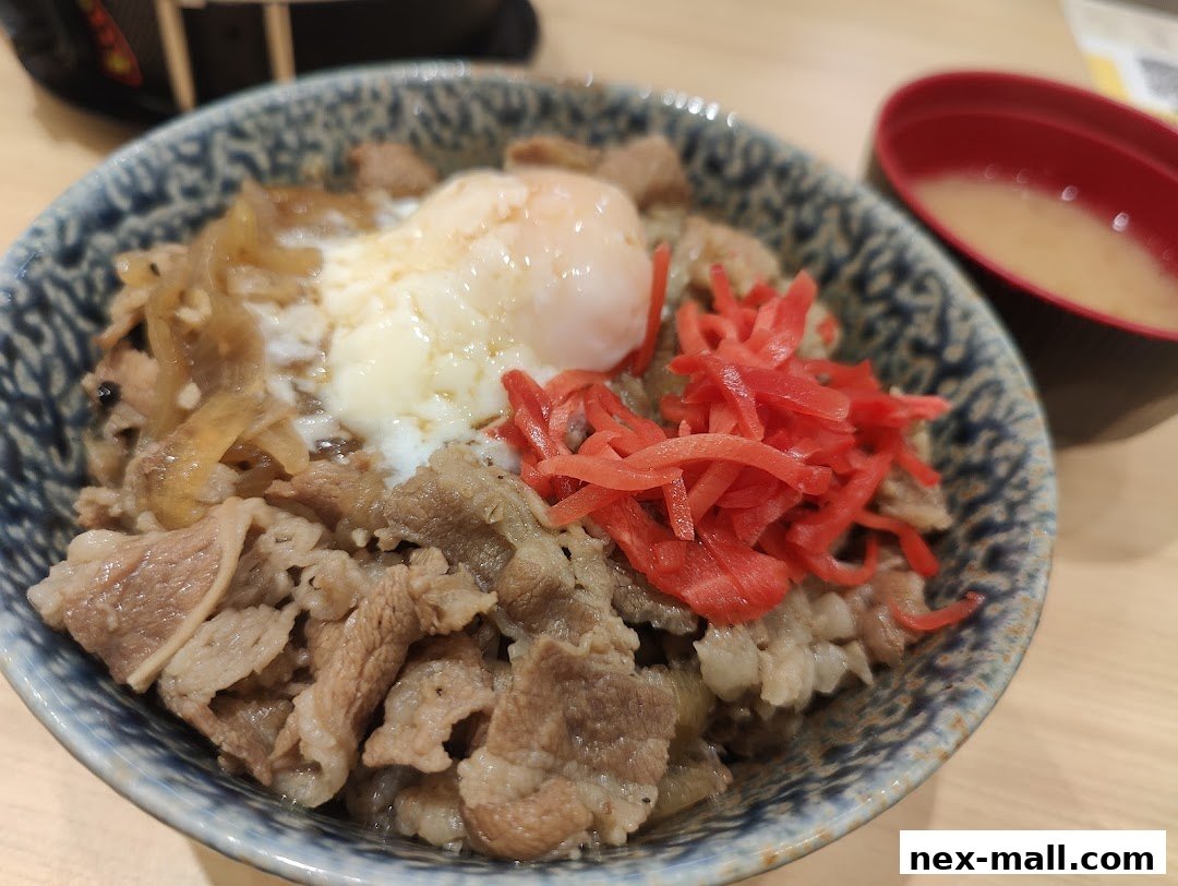 A close-up of a Japanese beef bowl with a soft-boiled egg and pickled ginger.