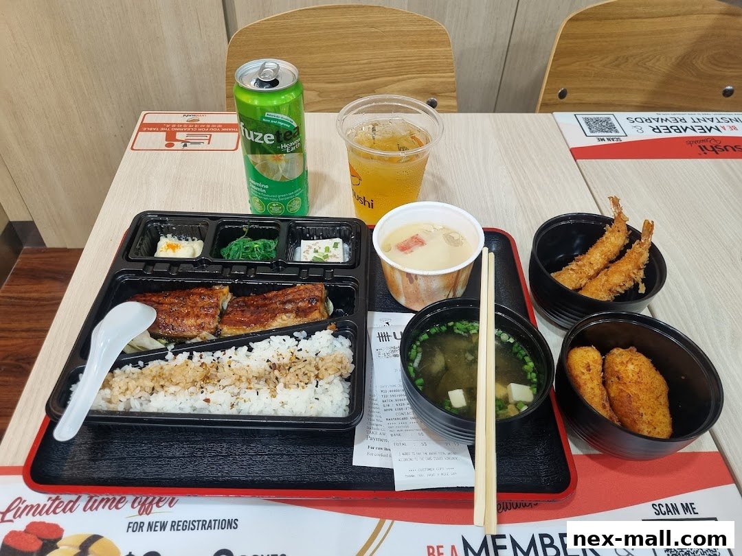 A bento box meal with eel, rice, side dishes, soup, and a drink.