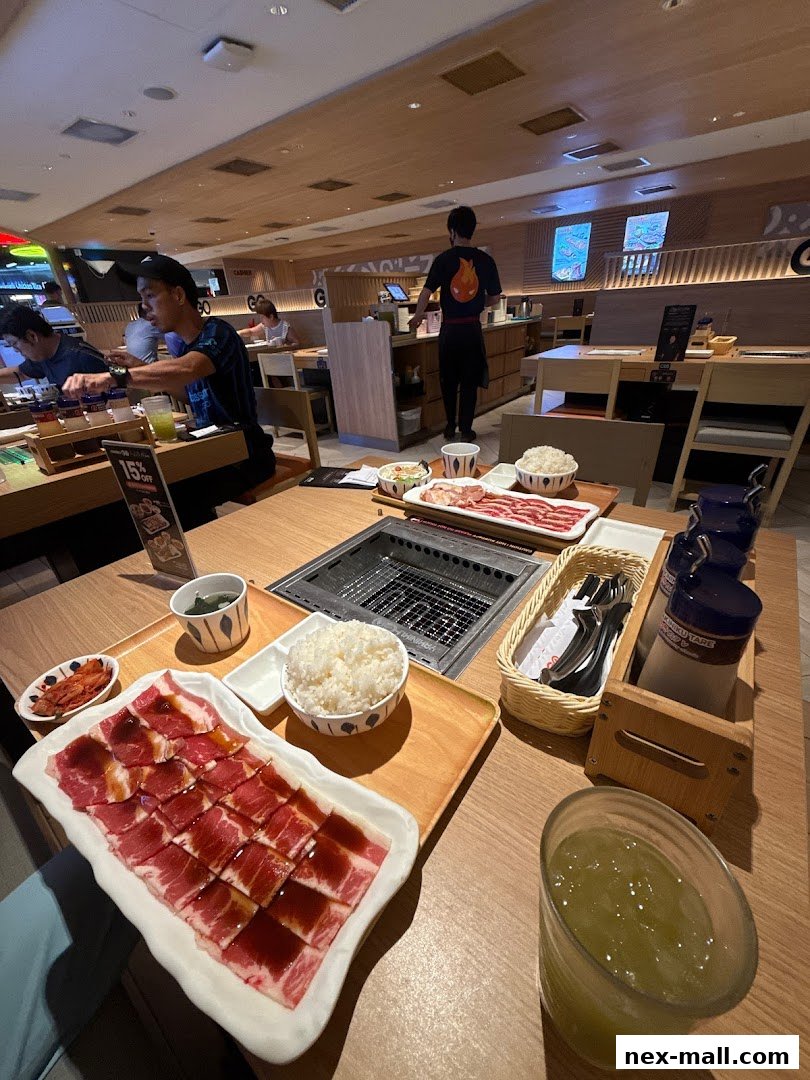 Diners enjoy a yakiniku meal with raw meat, rice, and side dishes at Yakiniku-GO NEX.