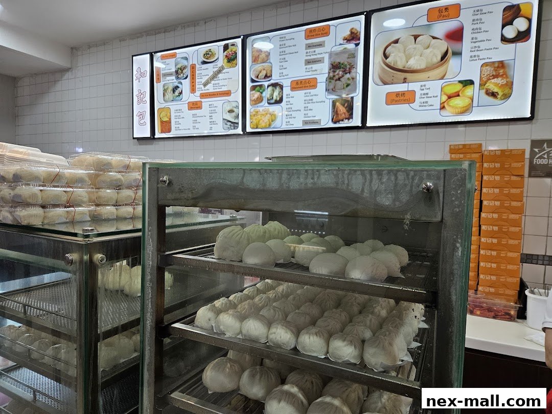 A display of freshly steamed buns and pastries at Ho Kee Pau, with a menu board above.