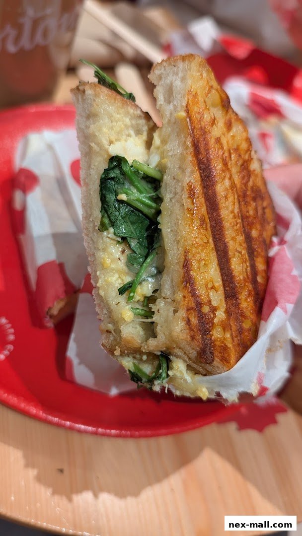 A close-up of a grilled sandwich with spinach and cheese filling on a red plate.