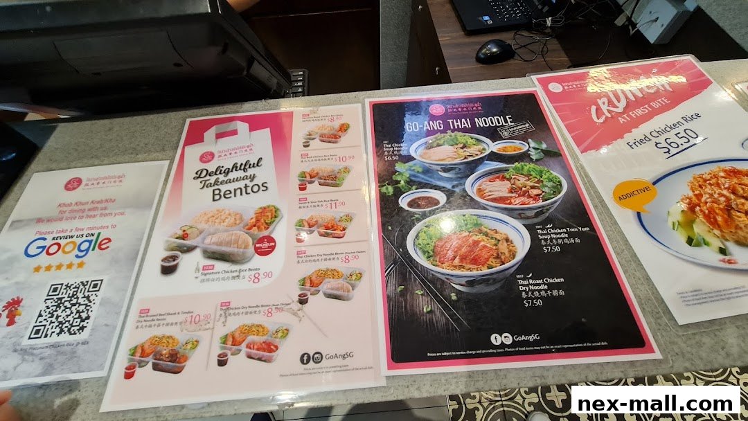 A display of menus and promotional flyers for Go-Ang Pratunam Chicken Rice, showcasing various dishes.