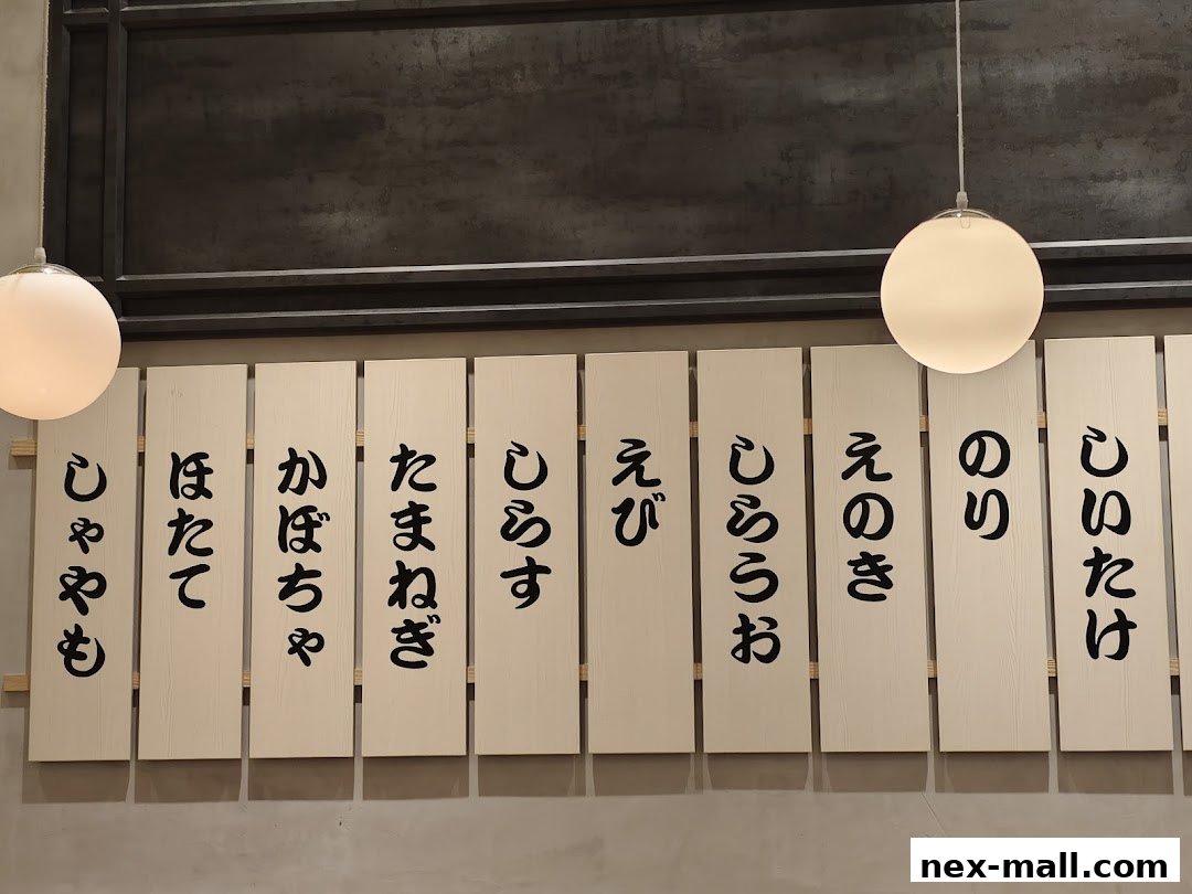 A menu board with Japanese text written on wooden planks, illuminated by pendant lights.