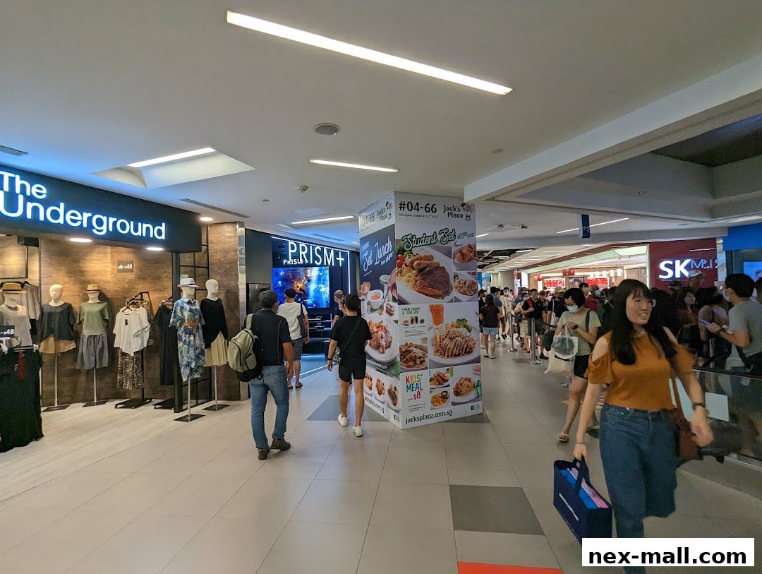 A busy shopping mall corridor with various shops and shoppers.