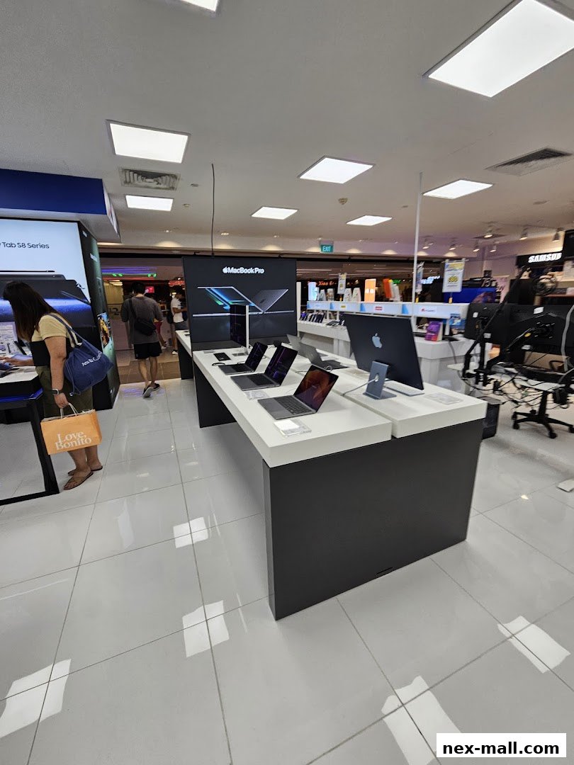 Interior view of an electronics store showcasing MacBook Pro laptops and other Apple products.