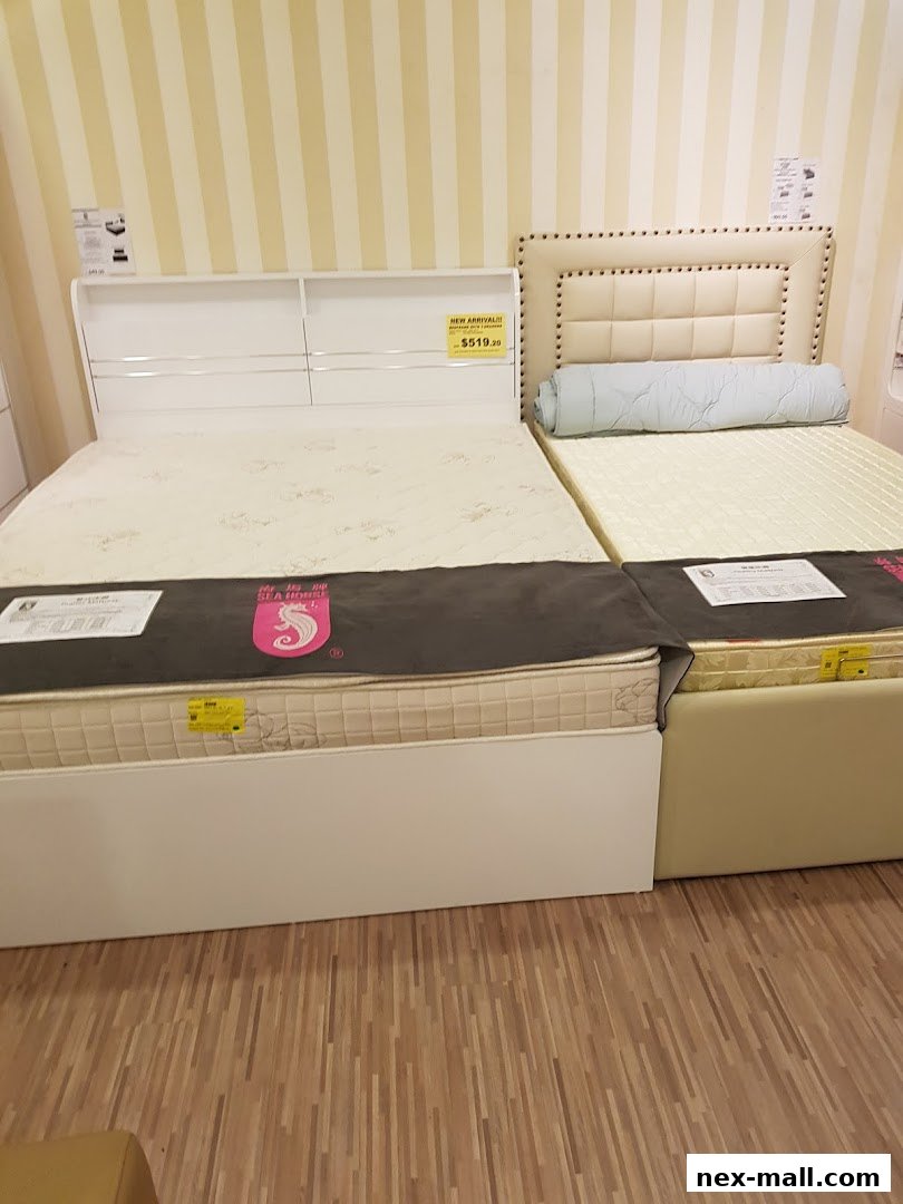 Two beds with mattresses and headboards are displayed in a store.