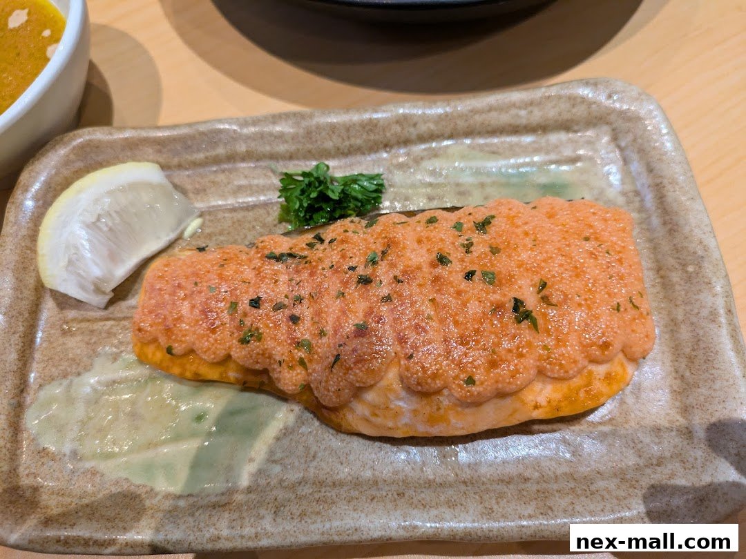 A piece of salmon topped with orange sauce and herbs, served with lemon and sauce.