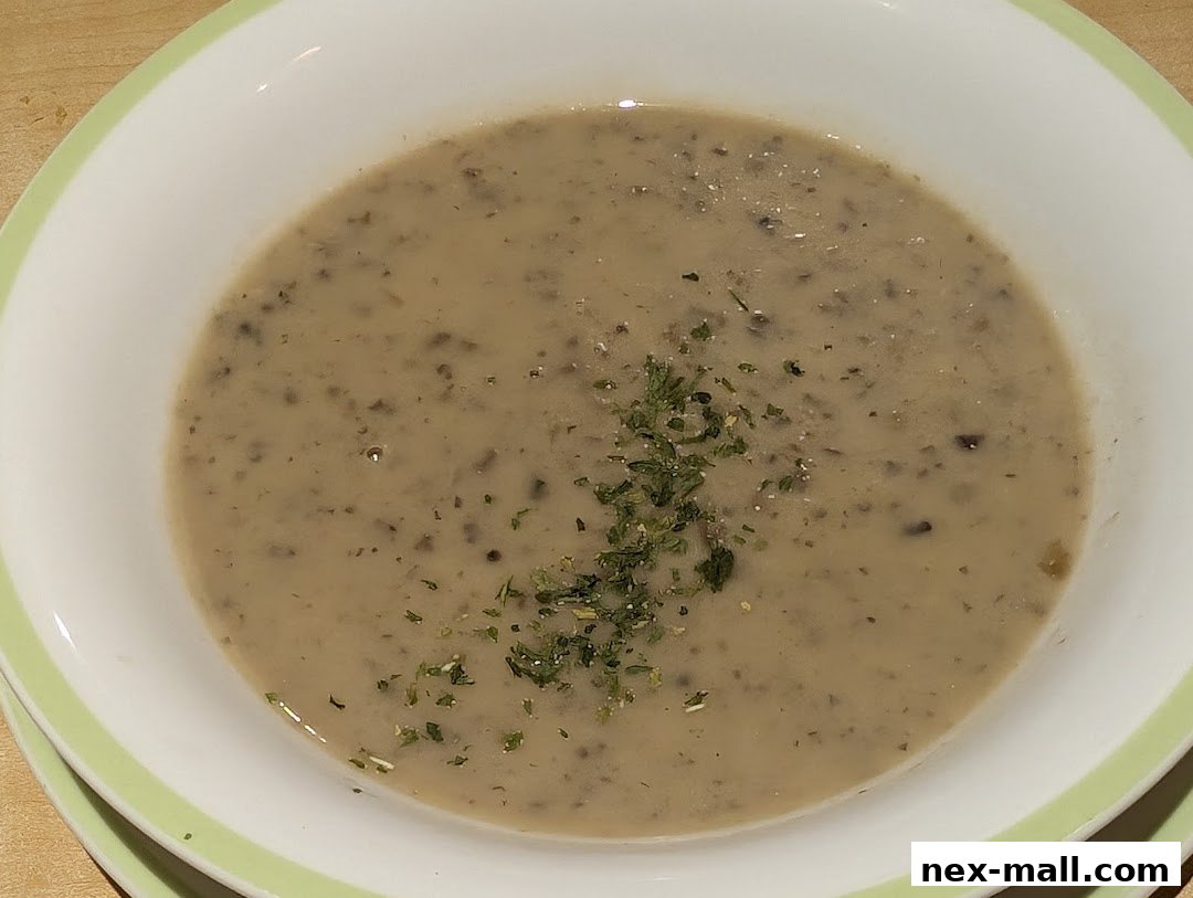 A close-up shot of a bowl of creamy mushroom soup garnished with parsley.
