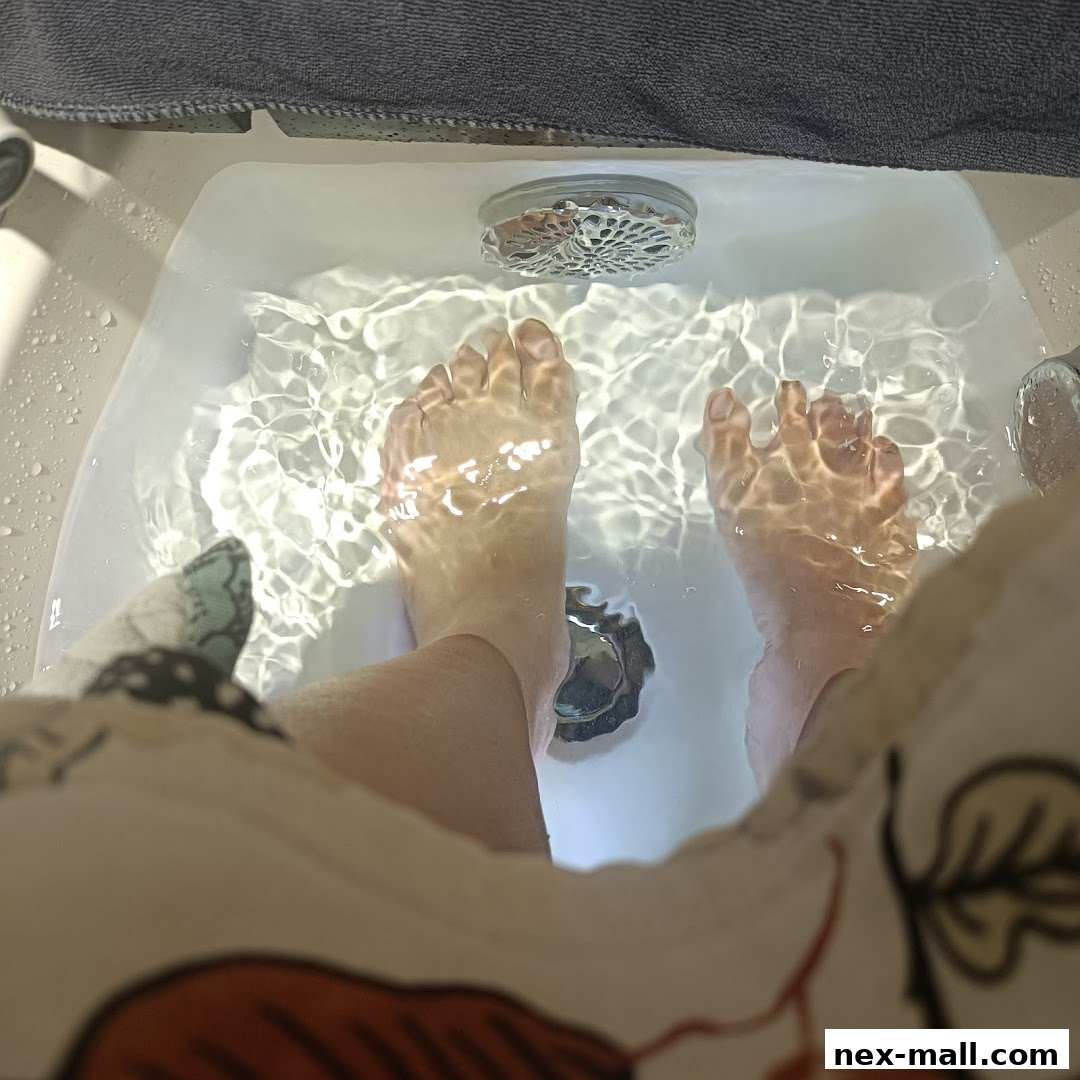 A person's feet soaking in a clean pedicure bath with rippling water.