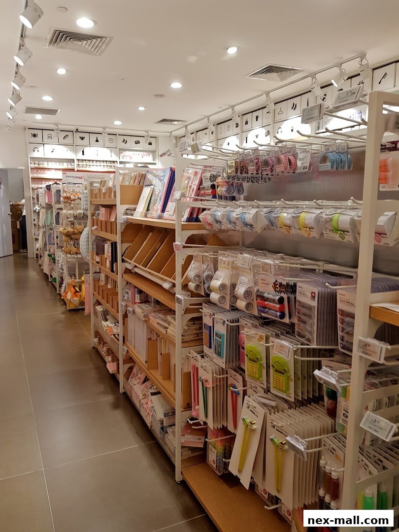 Interior view of a MINISO NEX store showcasing shelves filled with stationery, tape, and other lifestyle products.