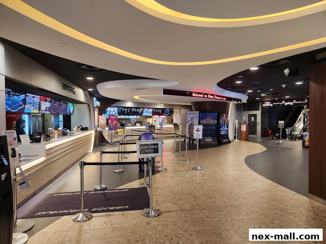 The interior of a cinema lobby with a box office, concession stand, and escalators.