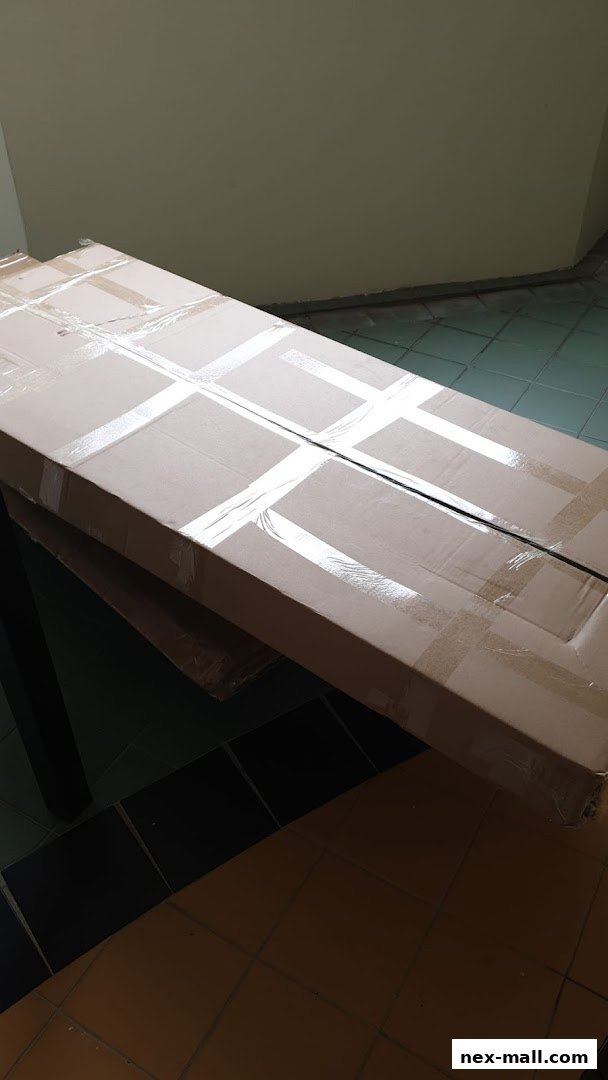 A long, cardboard box is taped shut and placed on a table.