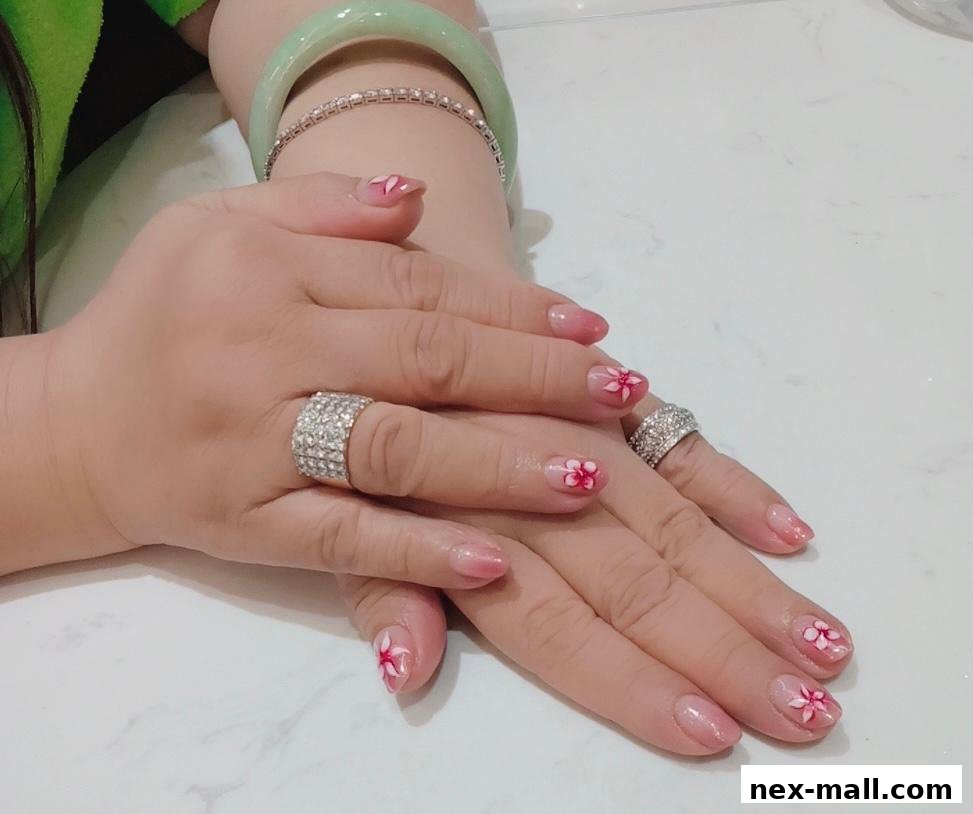 A close-up of hands with delicate floral nail art and sparkling rings.