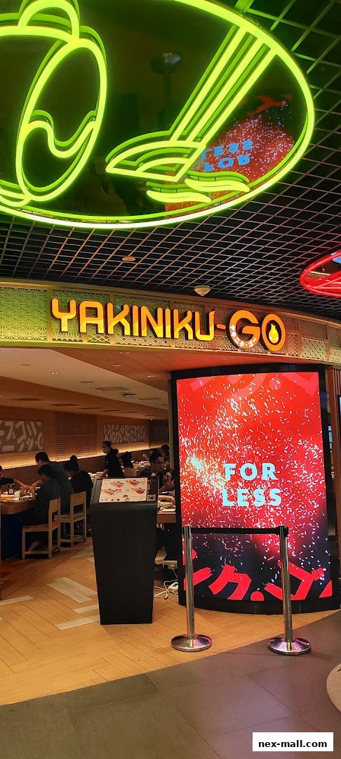 The entrance of Yakiniku-GO NEX restaurant with neon signs and a digital display.