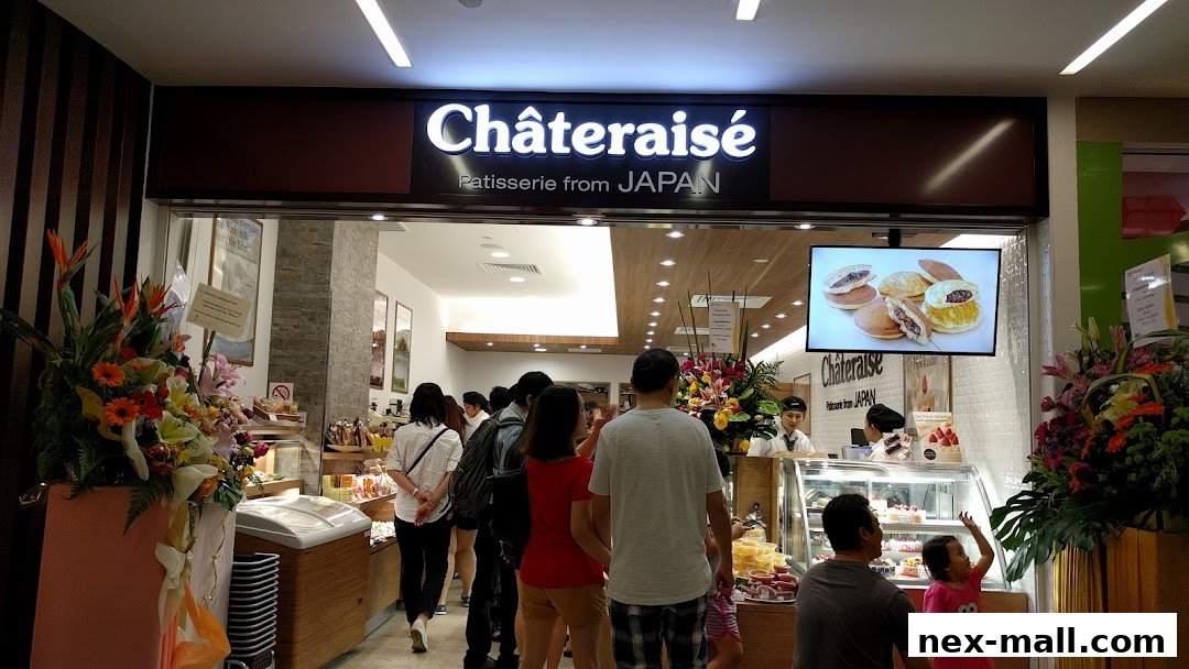 People queuing outside a Châteraisé patisserie shop with a display of pastries and flowers.