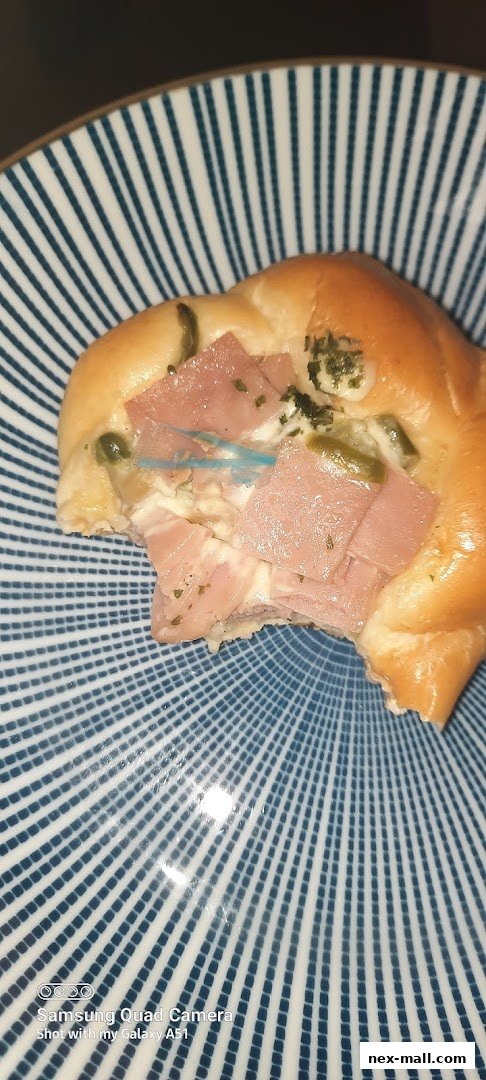 A close-up of a savory pastry with ham and green peppers on a striped plate.