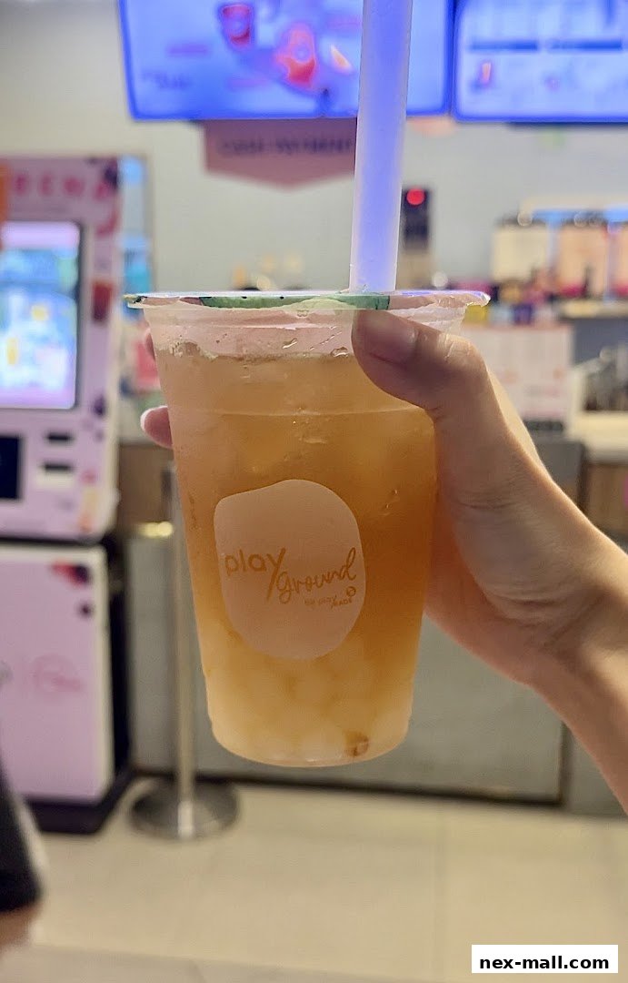 A hand holds a refreshing beverage with the PlayMade logo visible on the cup.