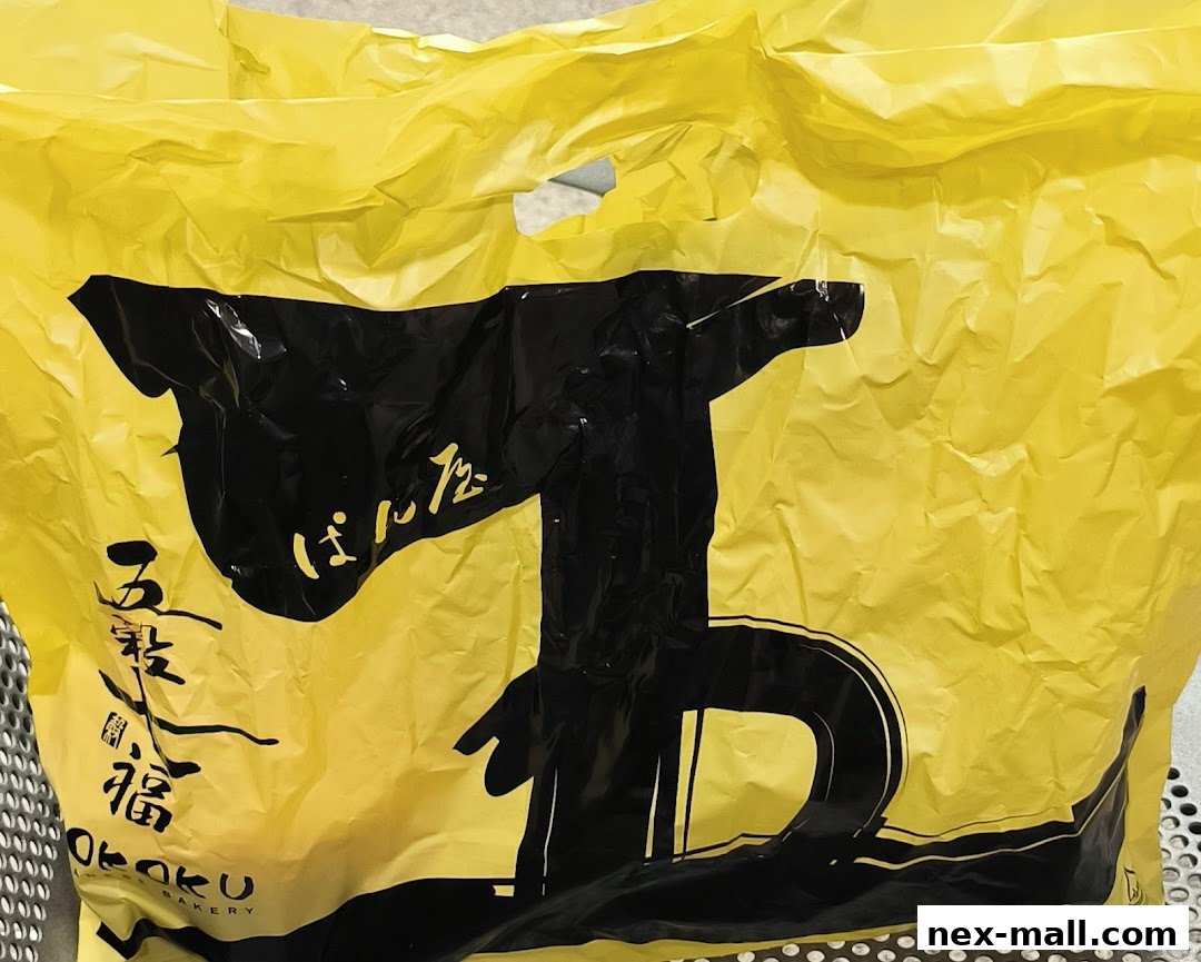 A crumpled yellow shopping bag with black Japanese text and a large black graphic.