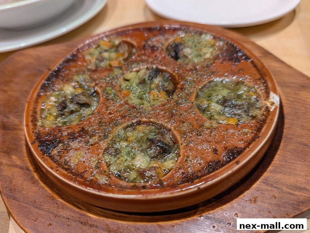 A close-up of escargots in garlic butter and herbs, served in a traditional dish.
