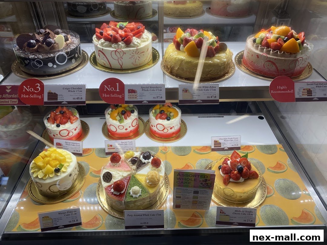 A display case filled with various beautifully decorated cakes, including fruit-topped and chocolate varieties.