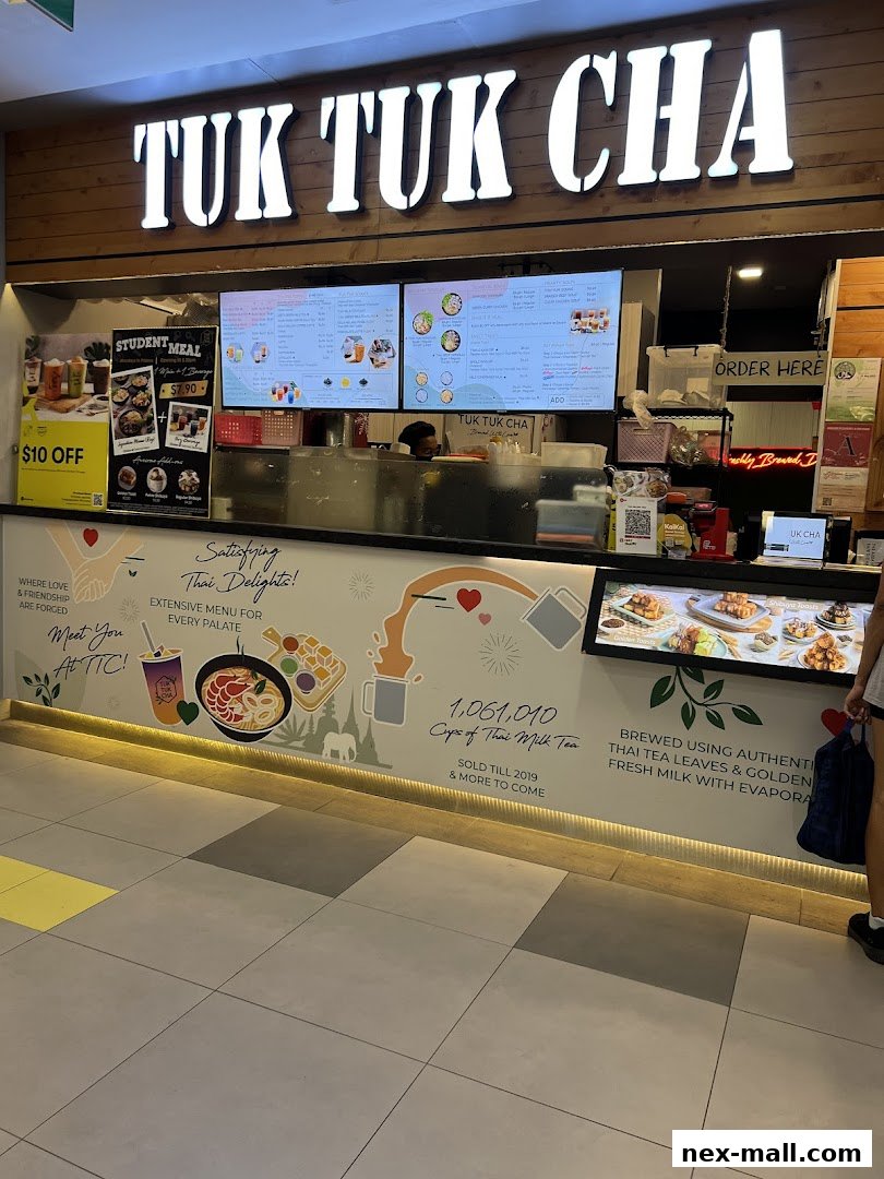 The storefront of Tuk Tuk Cha, featuring a large illuminated sign and digital menu boards.