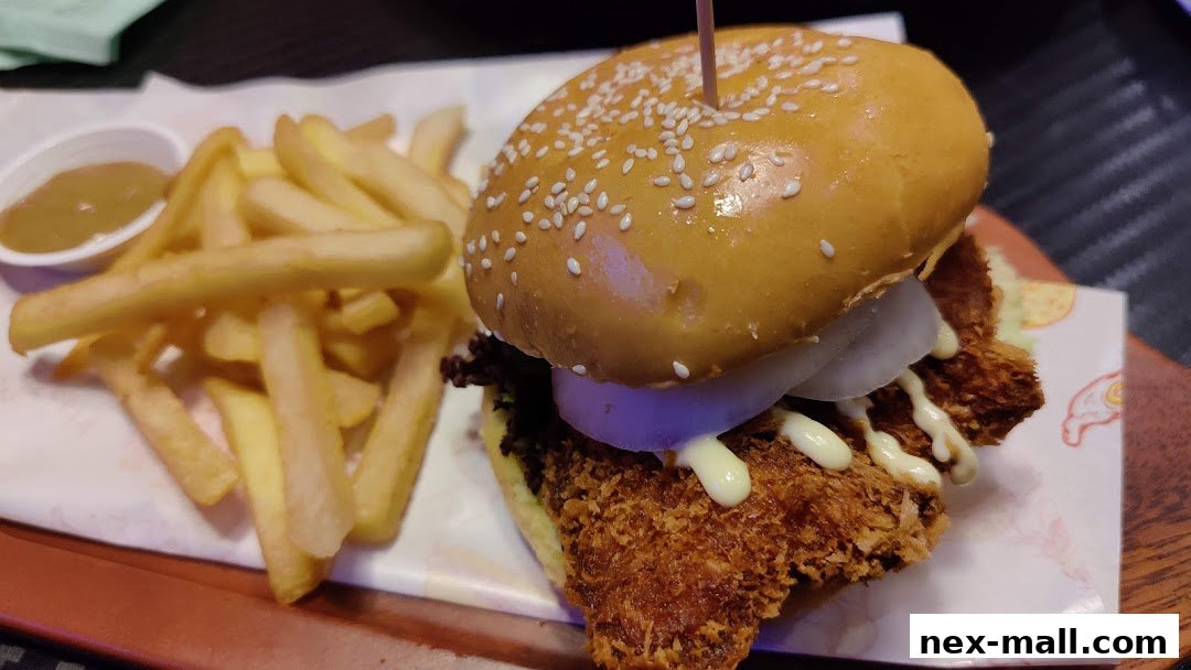 A close-up of a crispy chicken burger with fries and dipping sauce.