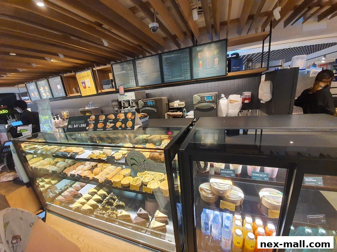 A Starbucks counter displaying a variety of pastries, cakes, and bottled beverages.