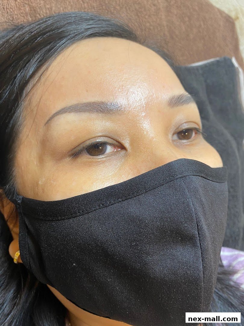 Close-up of a woman's face with a black mask, showing her eyebrows and eyes.