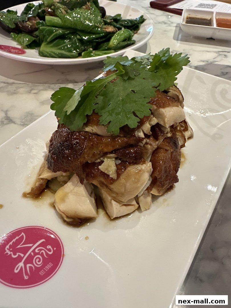 A plate of delicious chicken rice with fresh cilantro and a side of stir-fried vegetables.