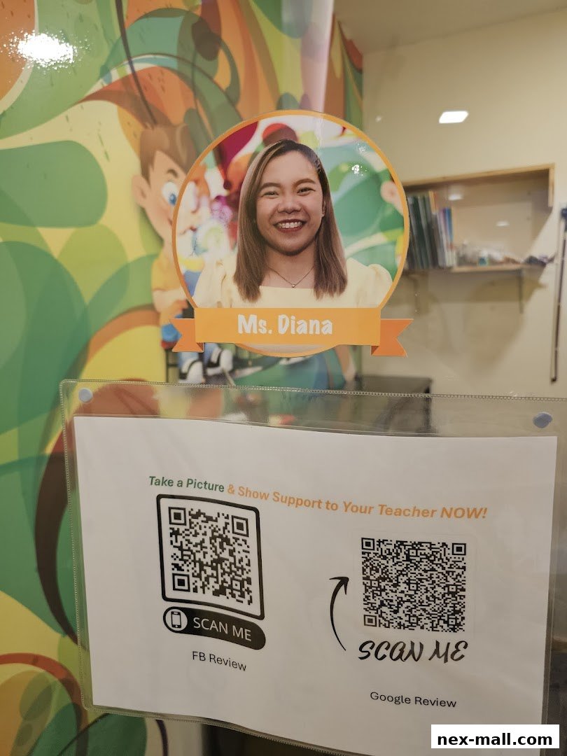 A sign with a teacher's photo and QR codes for reviews at Aureus Academy.