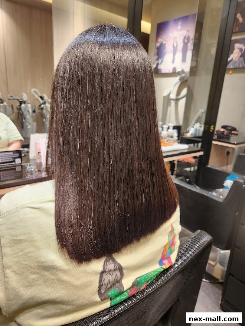 A person with freshly cut, sleek, dark brown hair sitting in a salon chair.