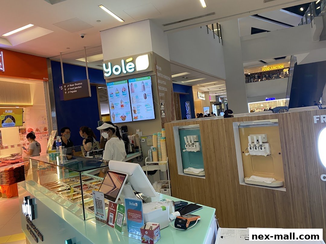 A Yolé shop interior with a display of frozen yogurt and staff serving customers.