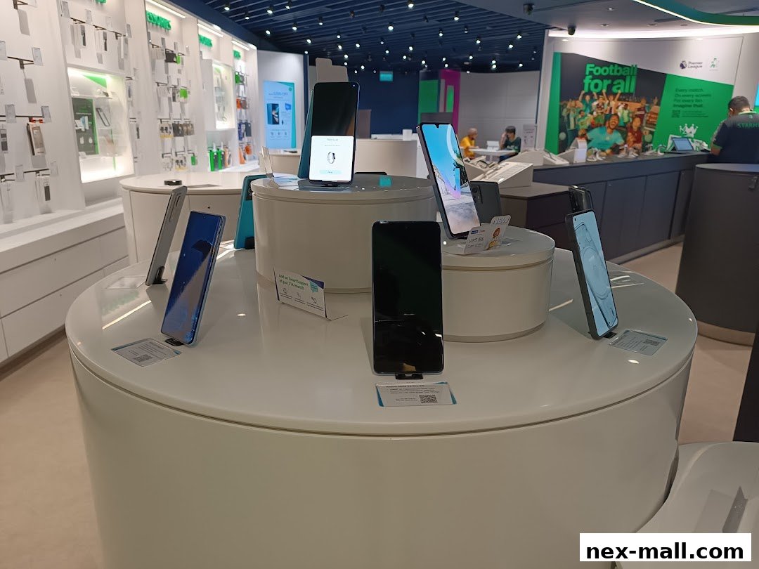 A display of various smartphones on white circular stands inside a modern electronics store.
