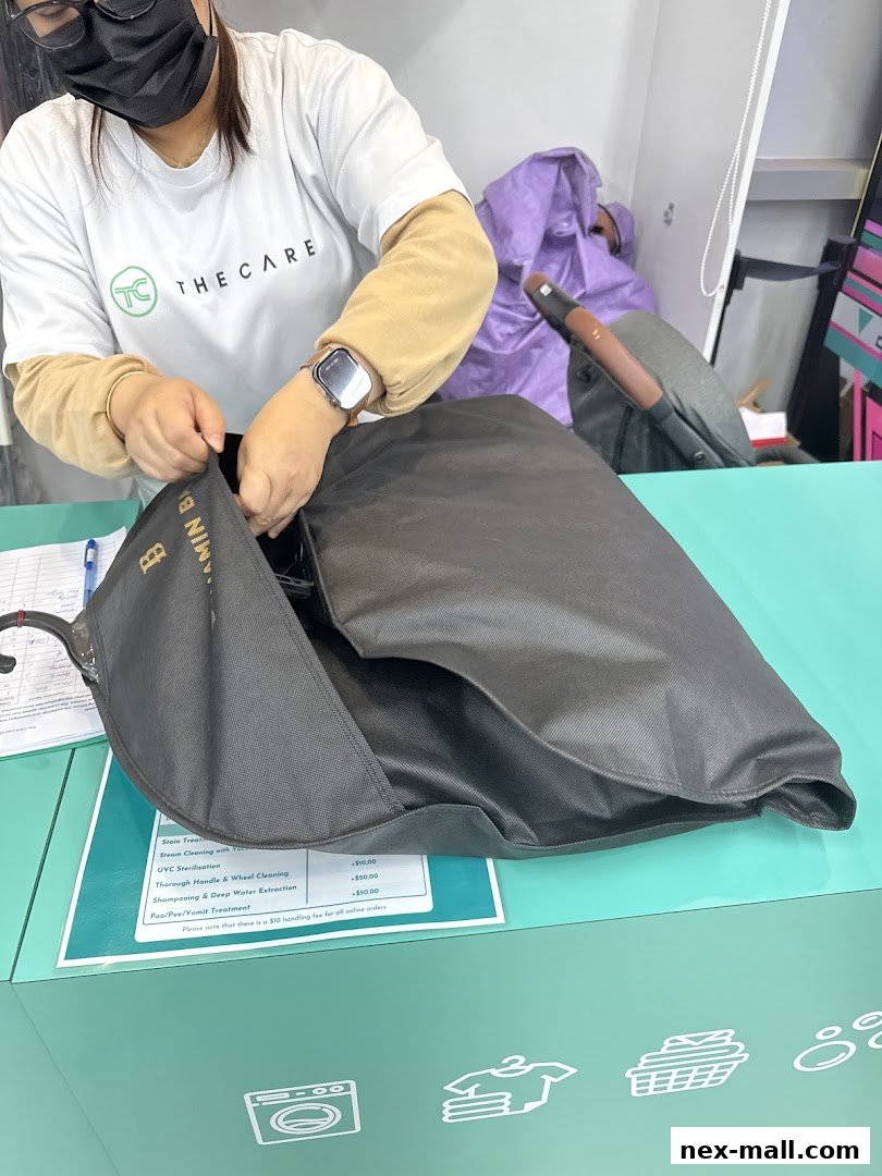 A person in a branded t-shirt is handling a garment bag at a counter.
