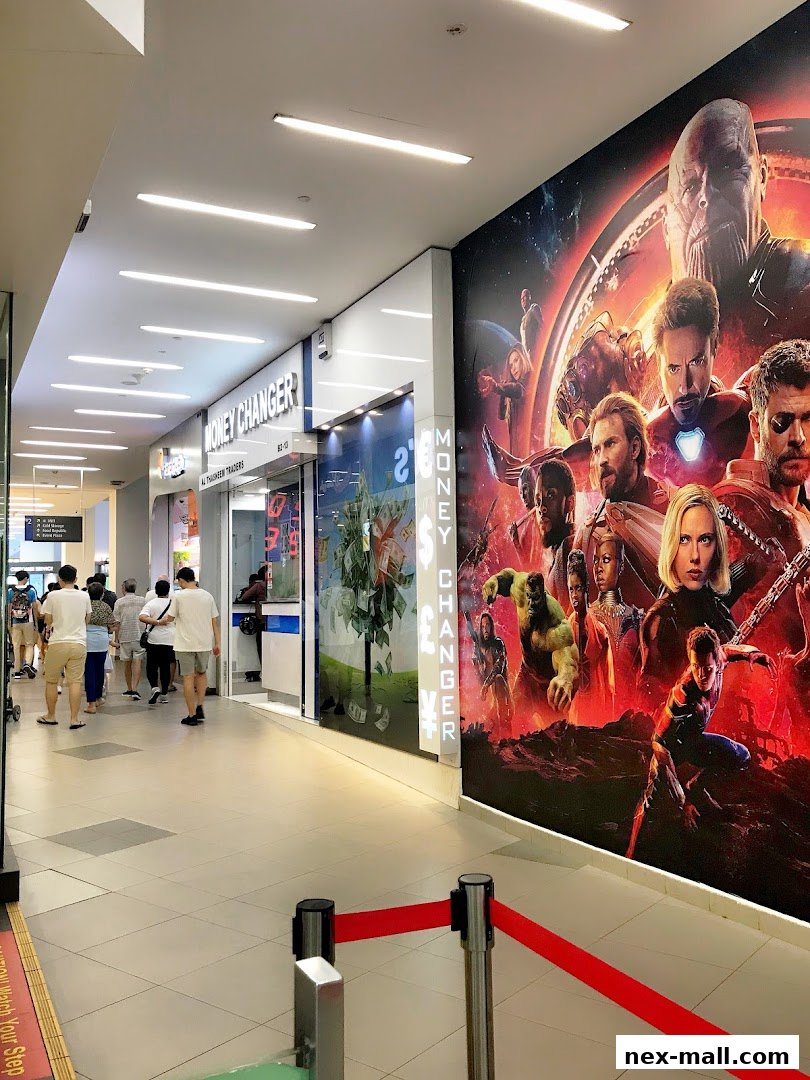 A money changer shop with a large Marvel movie poster on the adjacent wall.