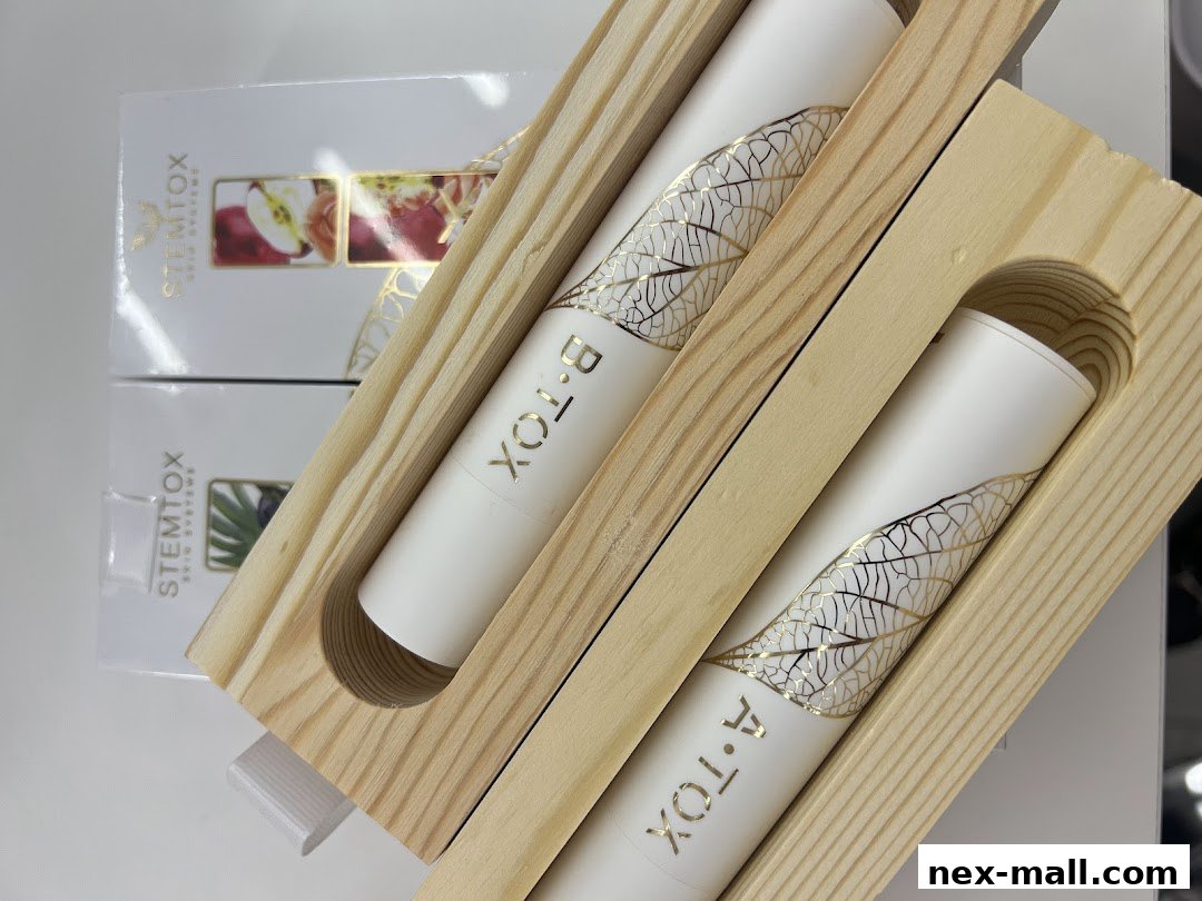 Two white cylindrical products with gold leaf designs in wooden holders.