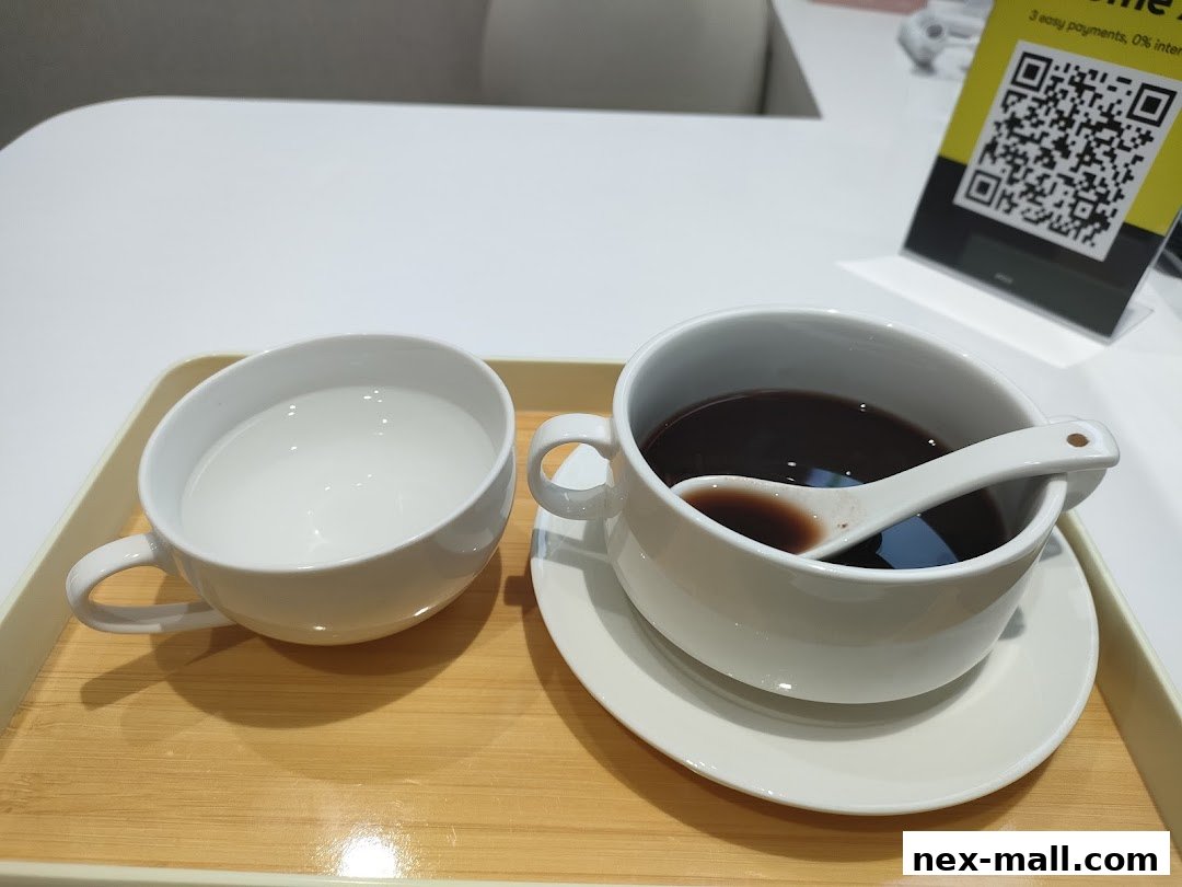 A cup of black sesame soup and a cup of water served on a tray.