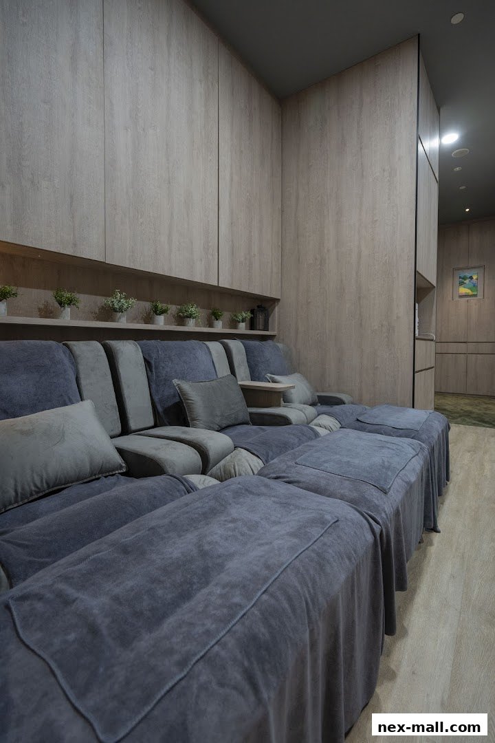 Comfortable reclining chairs with footrests covered in grey fabric, set against a backdrop of wooden paneling.