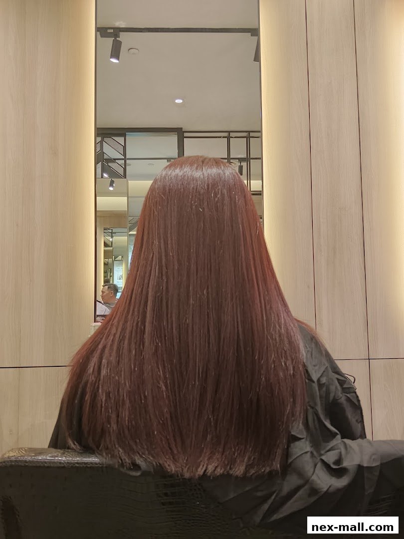 A person's long, reddish-brown hair is styled and reflected in a mirror.